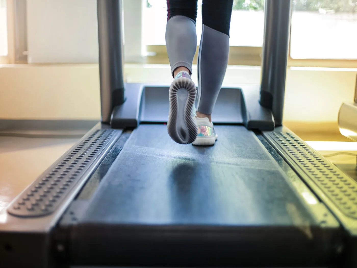 Coureuse sur un tapis de course, vue de dos, comme pendant une analyse de foulée
